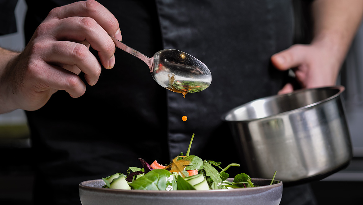 Chef pouring dressing over a salad
