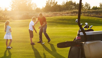 A Dad and two kids on a putting green