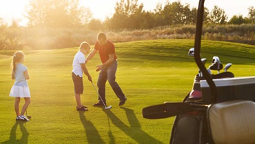 A Dad and two kids on a putting green