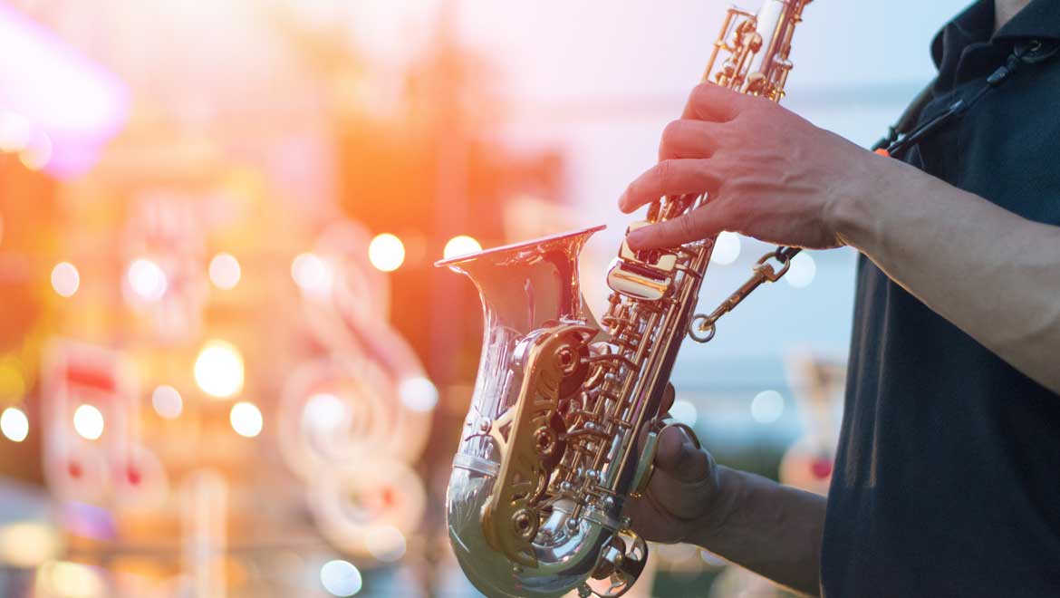 Man playing instrument in front of Christmas tree.