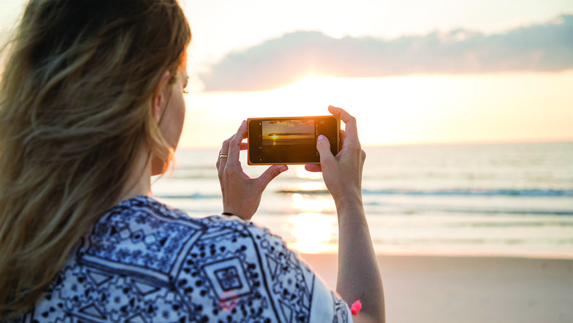 Woman taking picture at sunrise on the beach