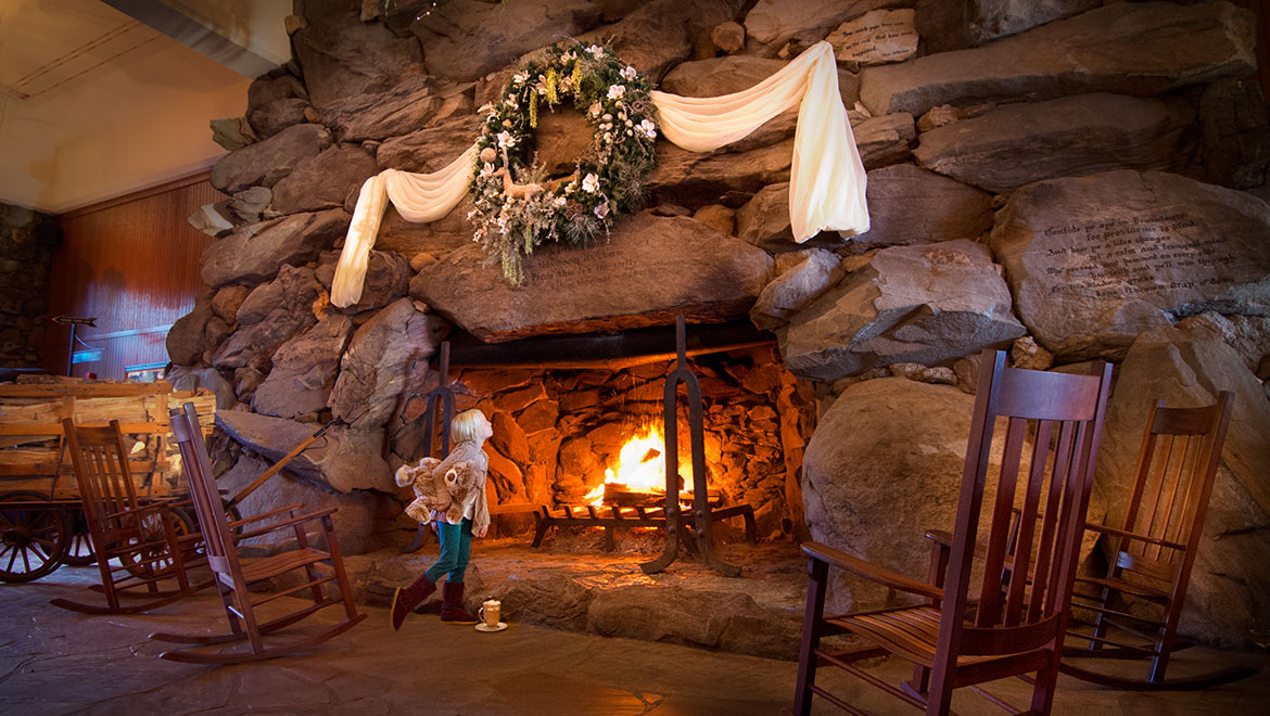 little girl looking at quote over fireplace with teddy bear and hot cocoa