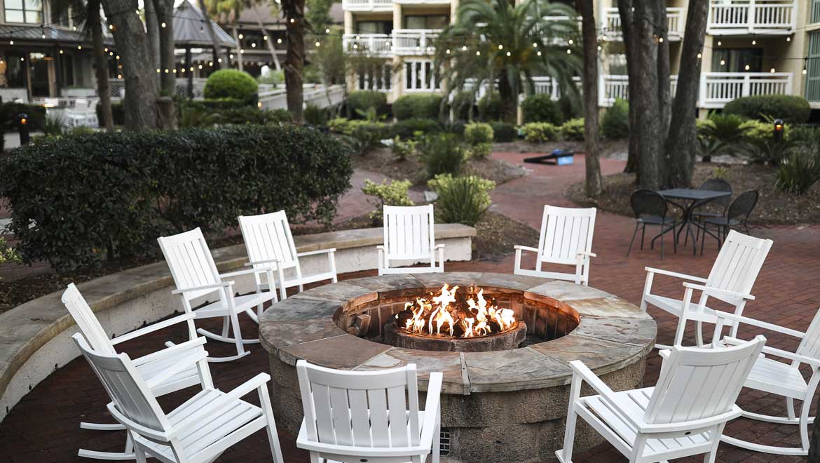 Firepit with white rocking chairs around it. 